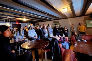 Postdocs at a pint of postdoc night listening to a speaker presenting their research 