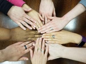 Several people putting their hands together in a circle